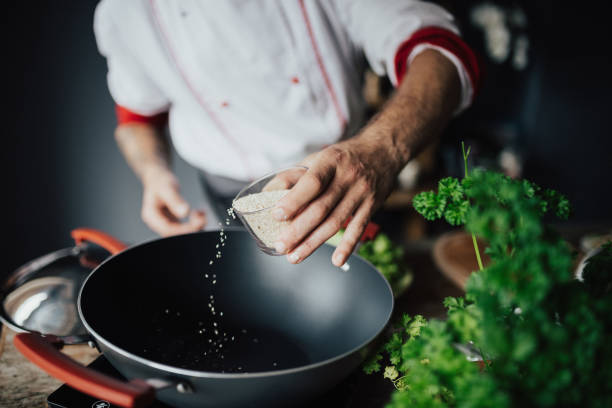 the-cook-pours-sesame-in-the-hot-pan-picture-id813740846.jpg